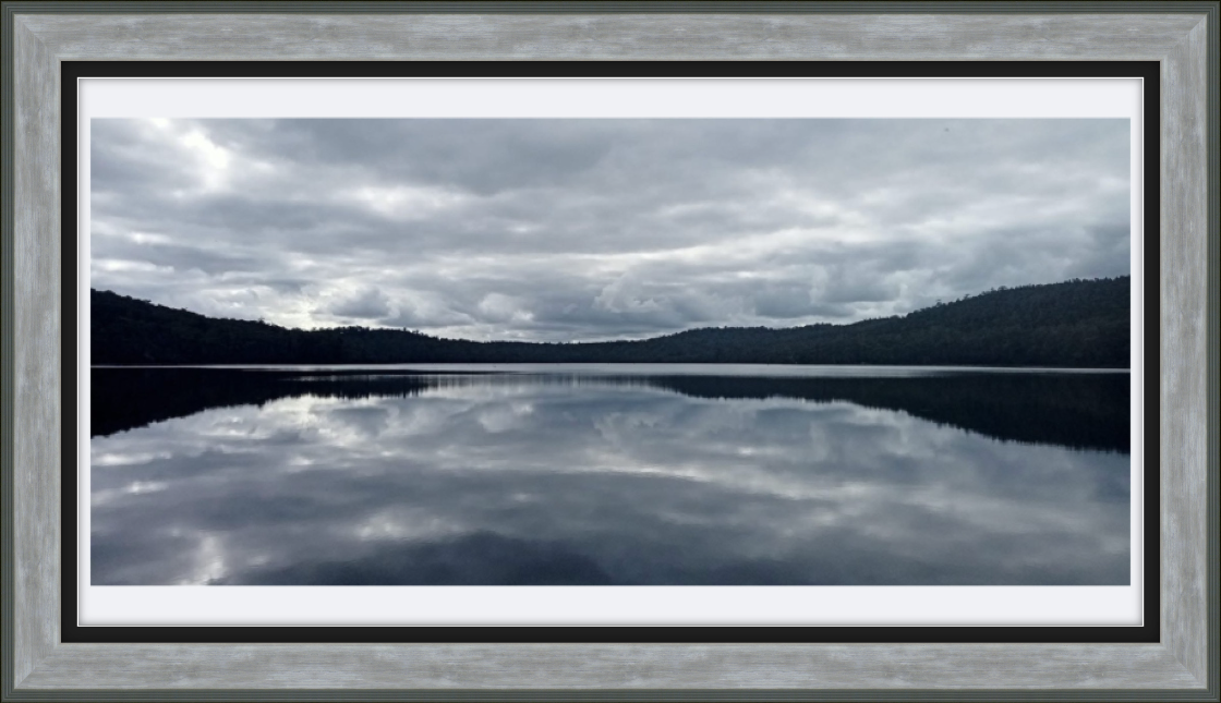 Framed photograph of a lake with mountains and cloudy sky